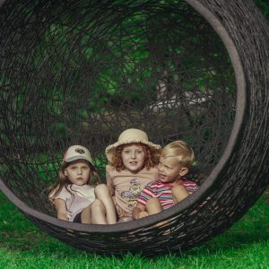 a group of kids sitting in a round black hanging chair